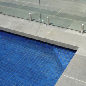 Bluestone pool coping tiles with a glass barrier.